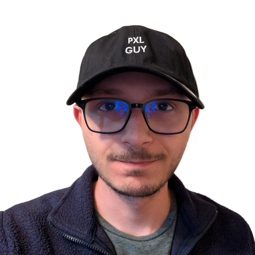 A man wearing a black baseball cap with 'PXL GUY' embroidered in white on the front, black-framed glasses, and a dark fleece zip-up jacket over a gray t-shirt, set against a dark background with a spotlight effect.